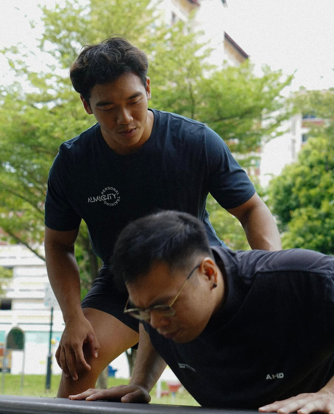 AlmightyPT personal trainer coaching a client through push-ups outdoors in Singapore