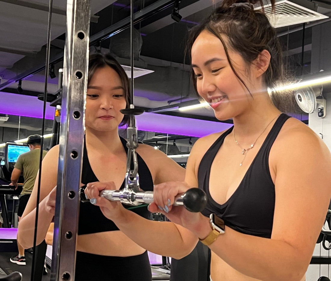 AlmightyPT female personal trainer coaching a woman through a cable strength training exercise in a Singapore gym